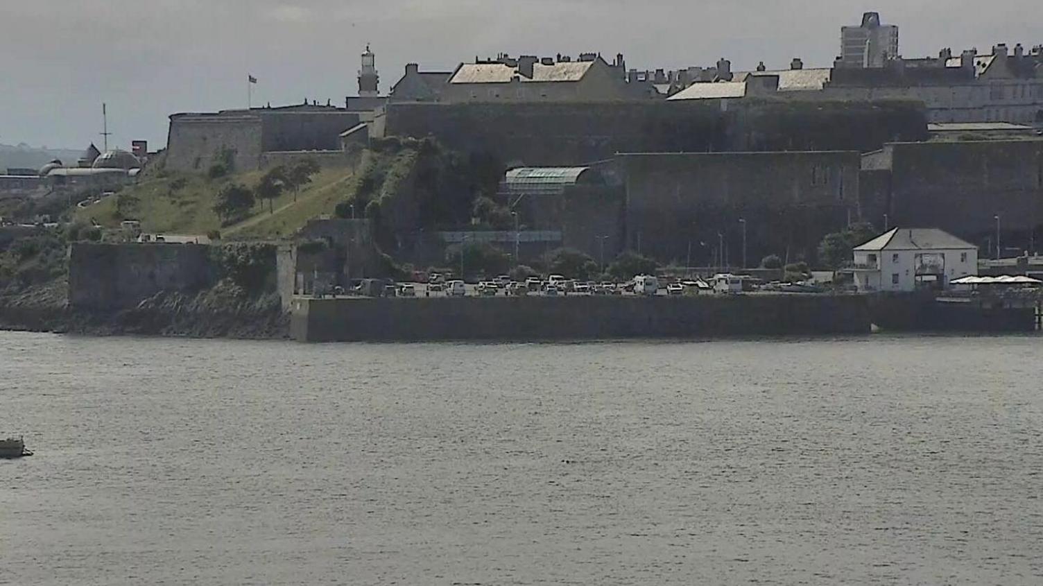 A CCTV picture of the harbour showing boats water and land in the background. The two swimmers in the water are barely visible. 