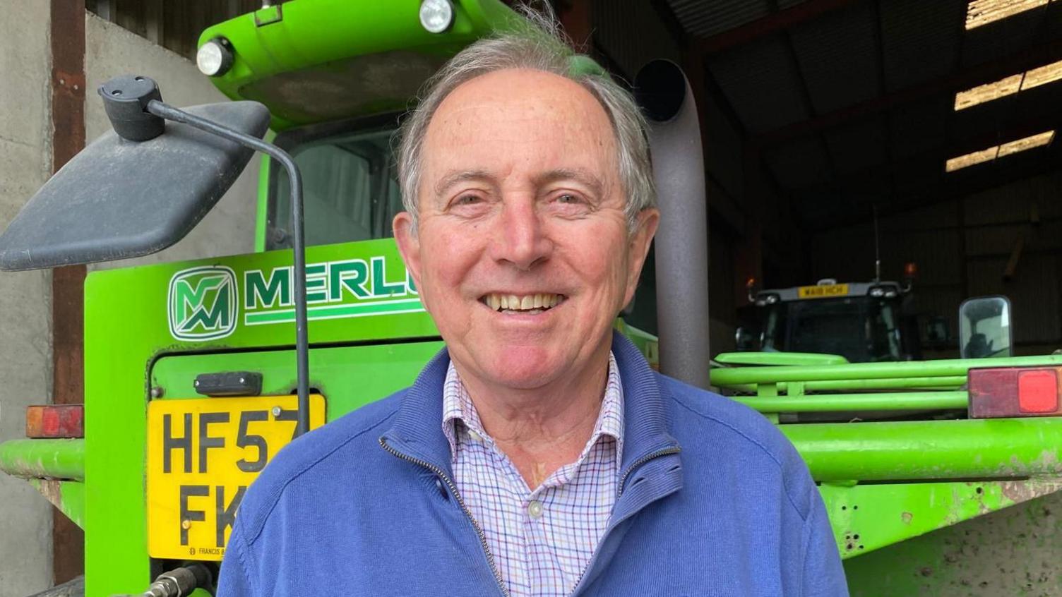 Arable farmer David Sedgman in front of a green agricultural vehicle