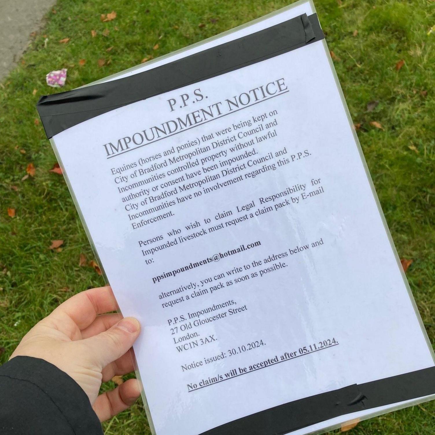 A male hand holding a plastic laminated sheet of white A4 paper with black writing. 