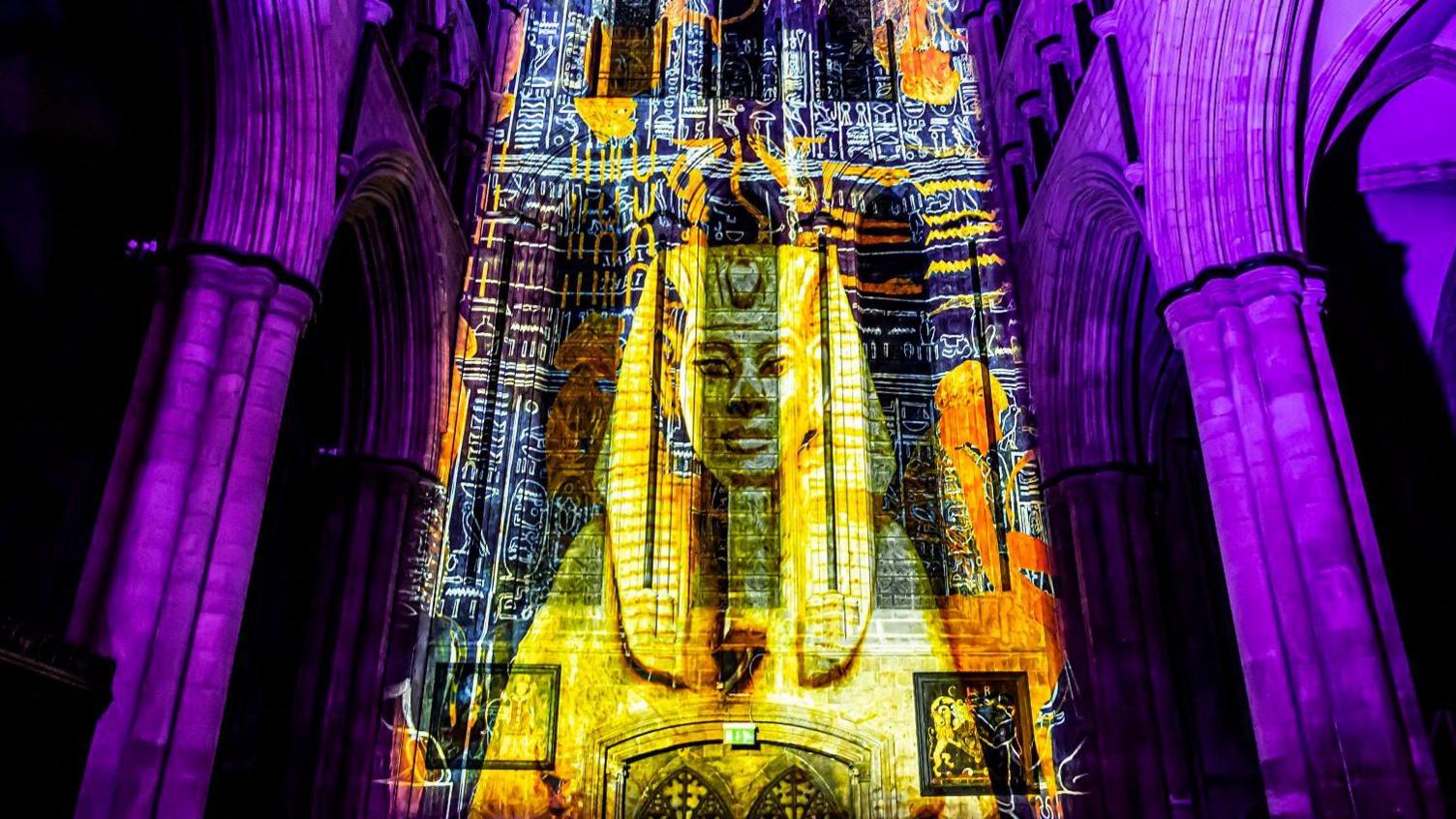 A projection on an interior wall of a cathedral showing a pharaoh. 