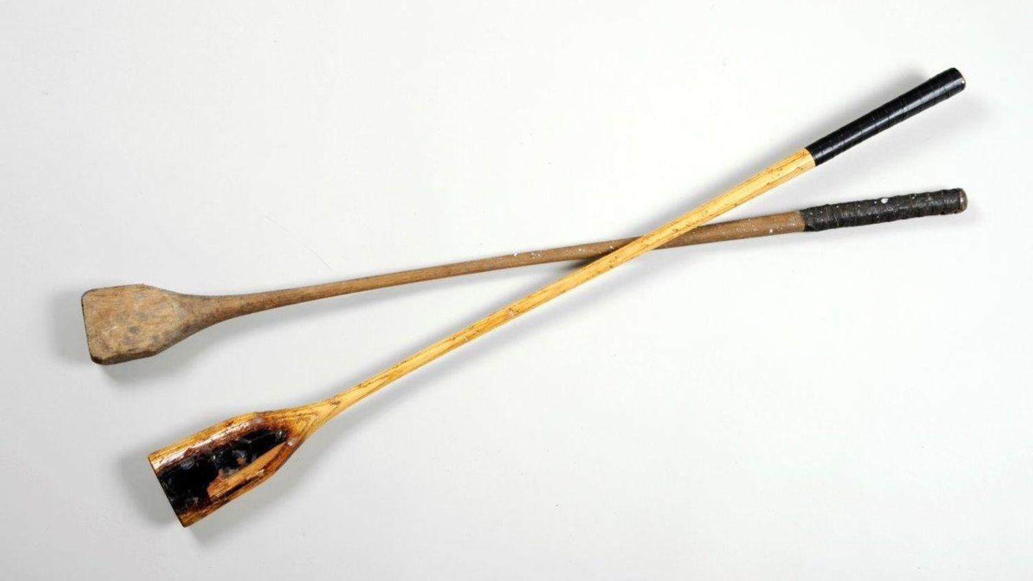 A pair of wooden nipsy sticks that are dark in colour with black handles.
