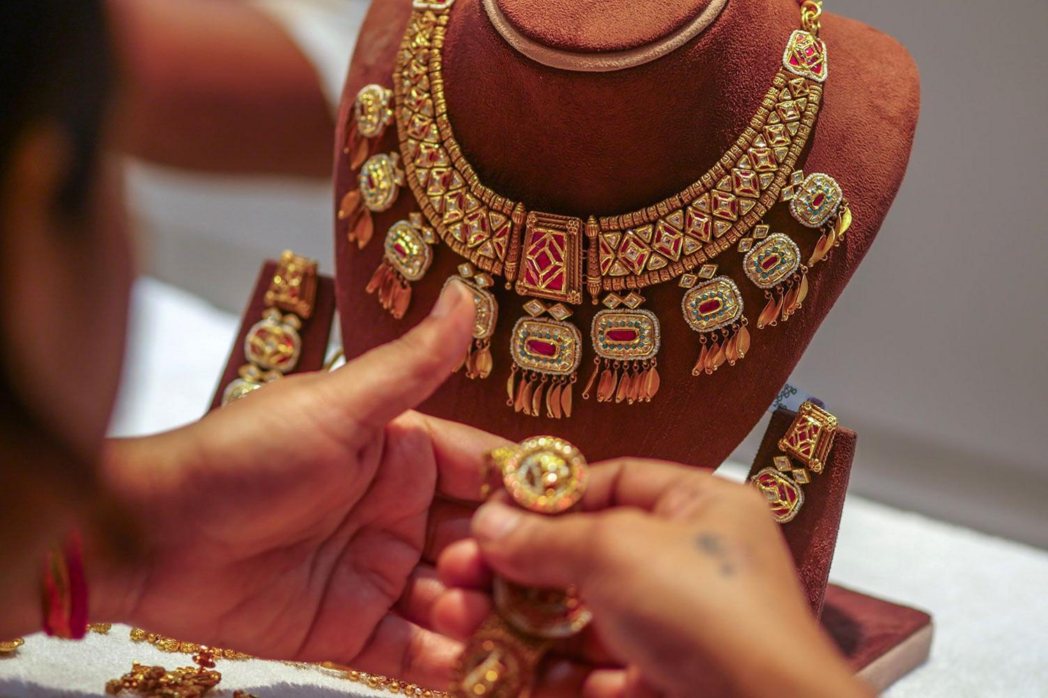 A woman looks at a gold necklace and earrings at a jewellery store at Zaveri Bazaar during the festival of Dhanteras in Mumbai, on Tuesday