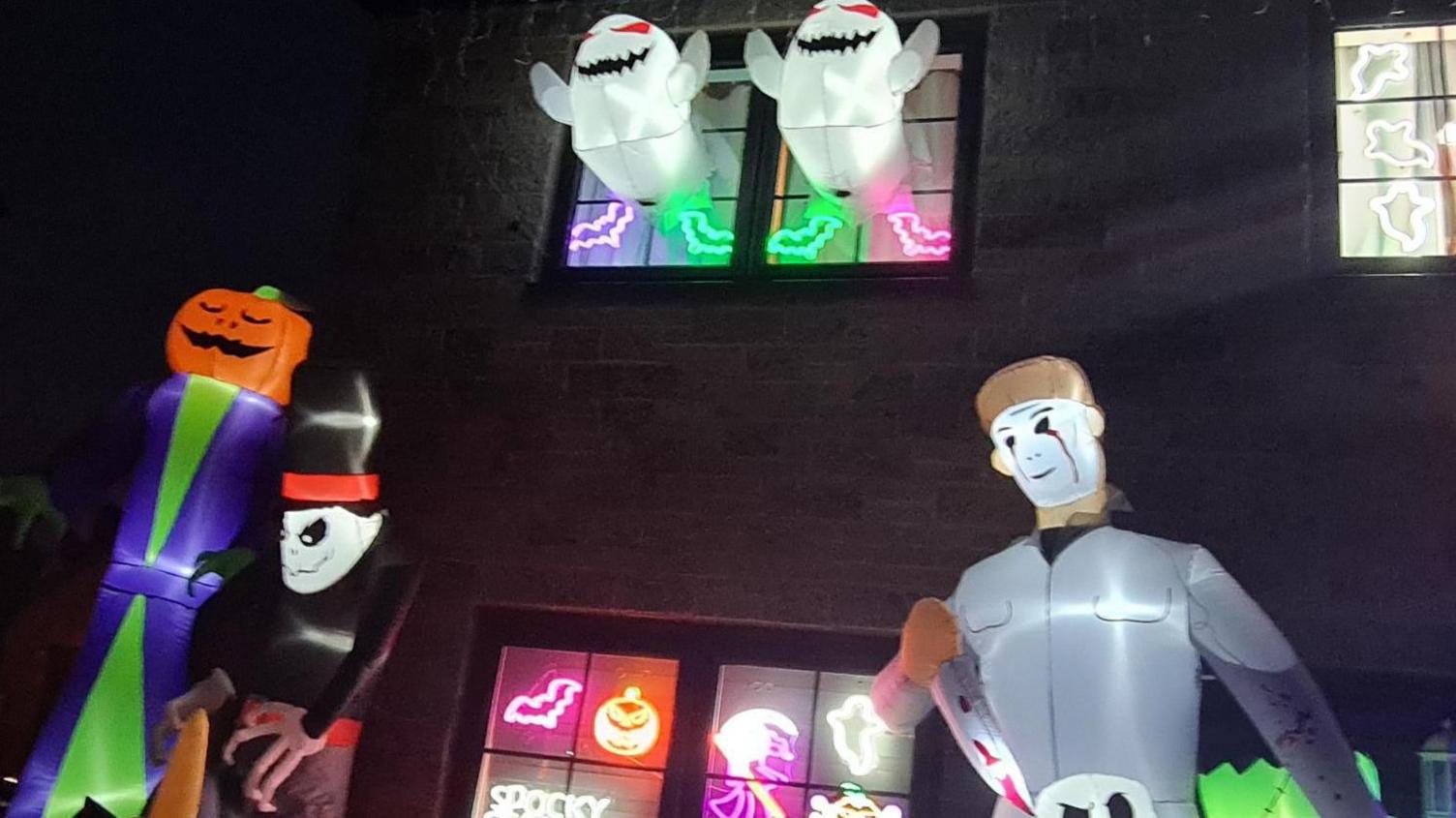 Inflatable ghosts burst through the windows of a house, while other inflatable figures including an undertaker and a knife-wielding man stand in the front garden.  