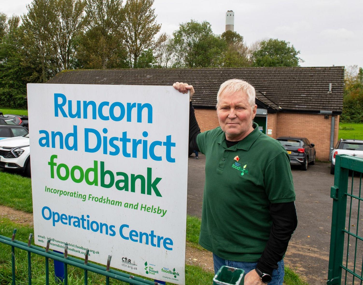 Eddie Thompson, manager of the Runcorn Foodbank at the charities main distribution centre, standing next to sign. Incinerator can be seen in the distance. 