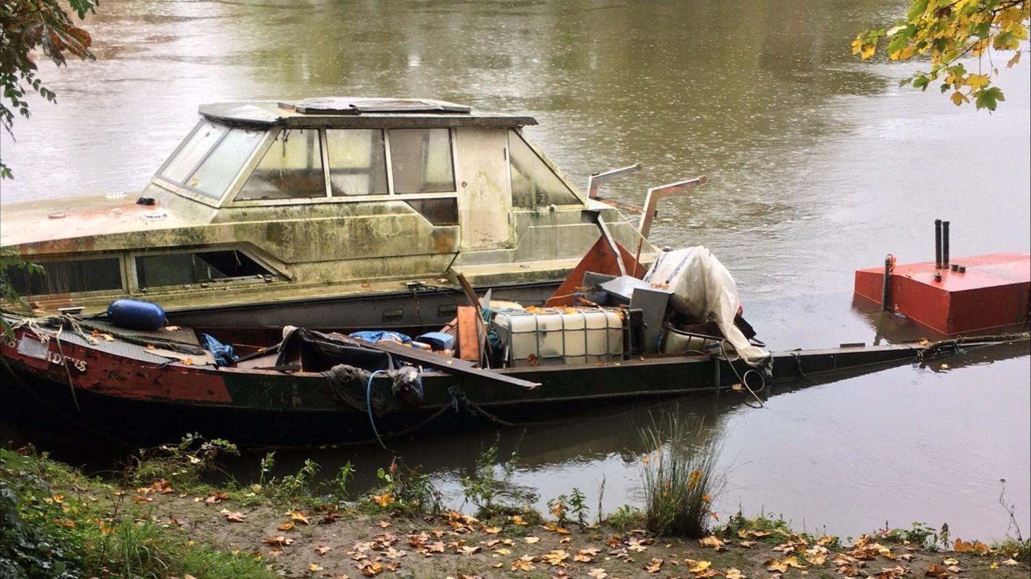 two of the boats, appearing mouldy and broken, on the River Thames