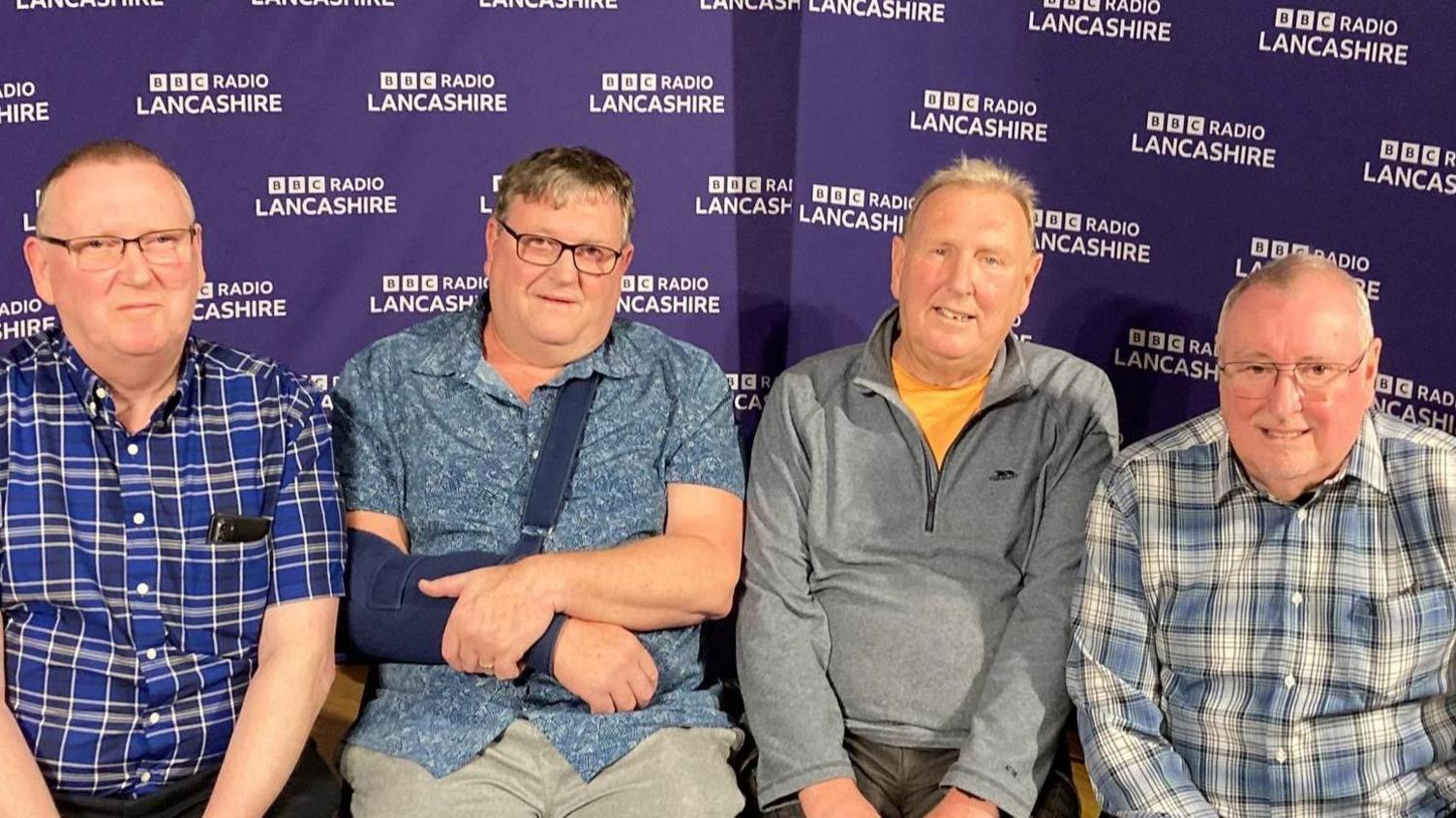 Brothers (left to right) Tim, Andy, Jim and Steve Hastings. Tim wears glasses and a blue-and-black checked shirt. Andy wears glasses, his arm in a sling. Jim wears a yellow t-shirt and grey fleece. Steve is wearing glasses and a blue-and-white checked shirt