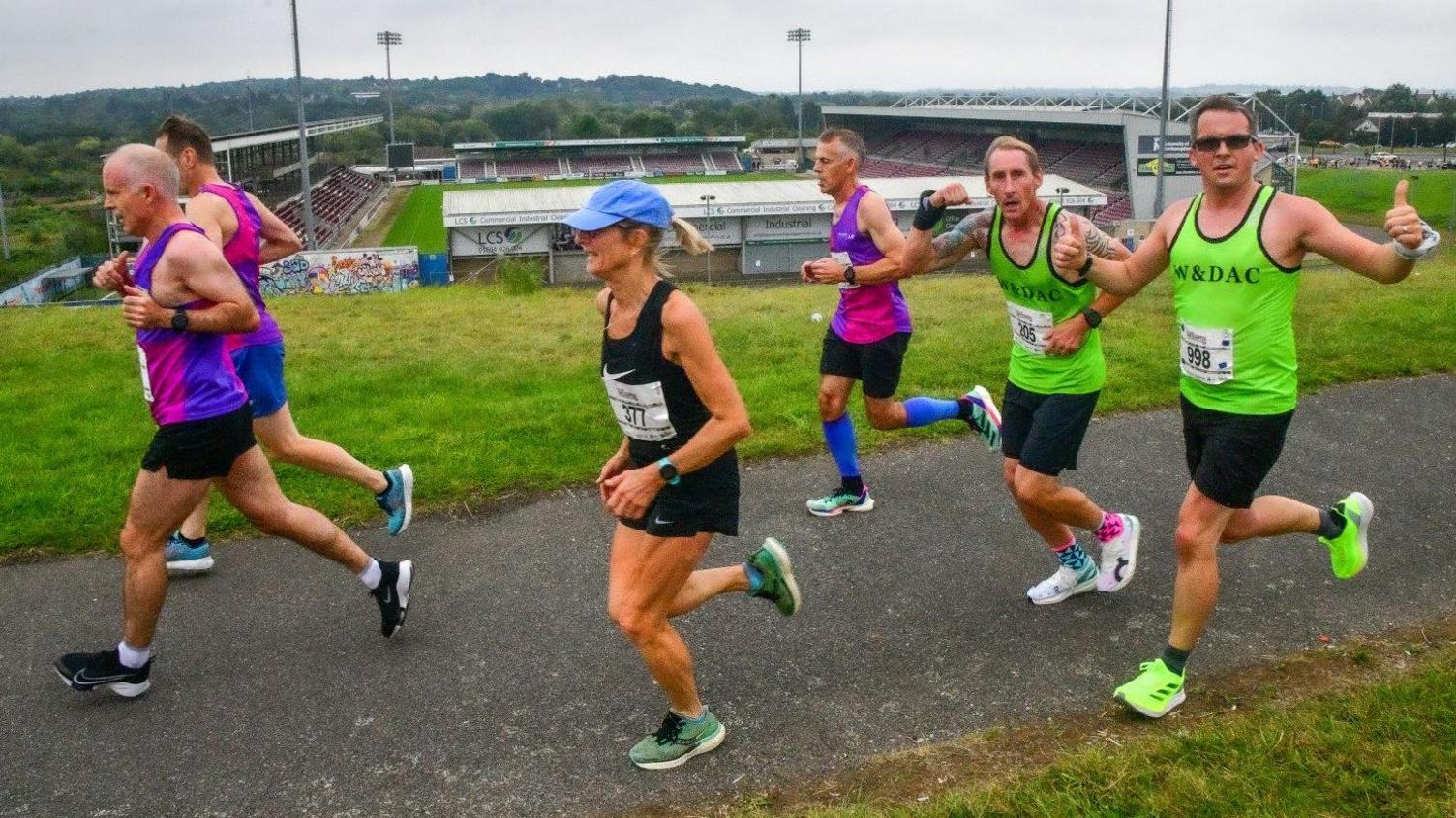 Group of runners going past Northampton Town's Sixfields Stadium