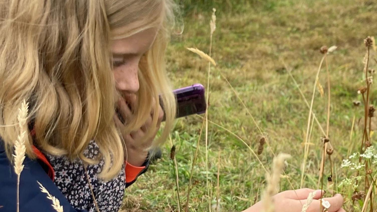 A young girl crouched on the grass