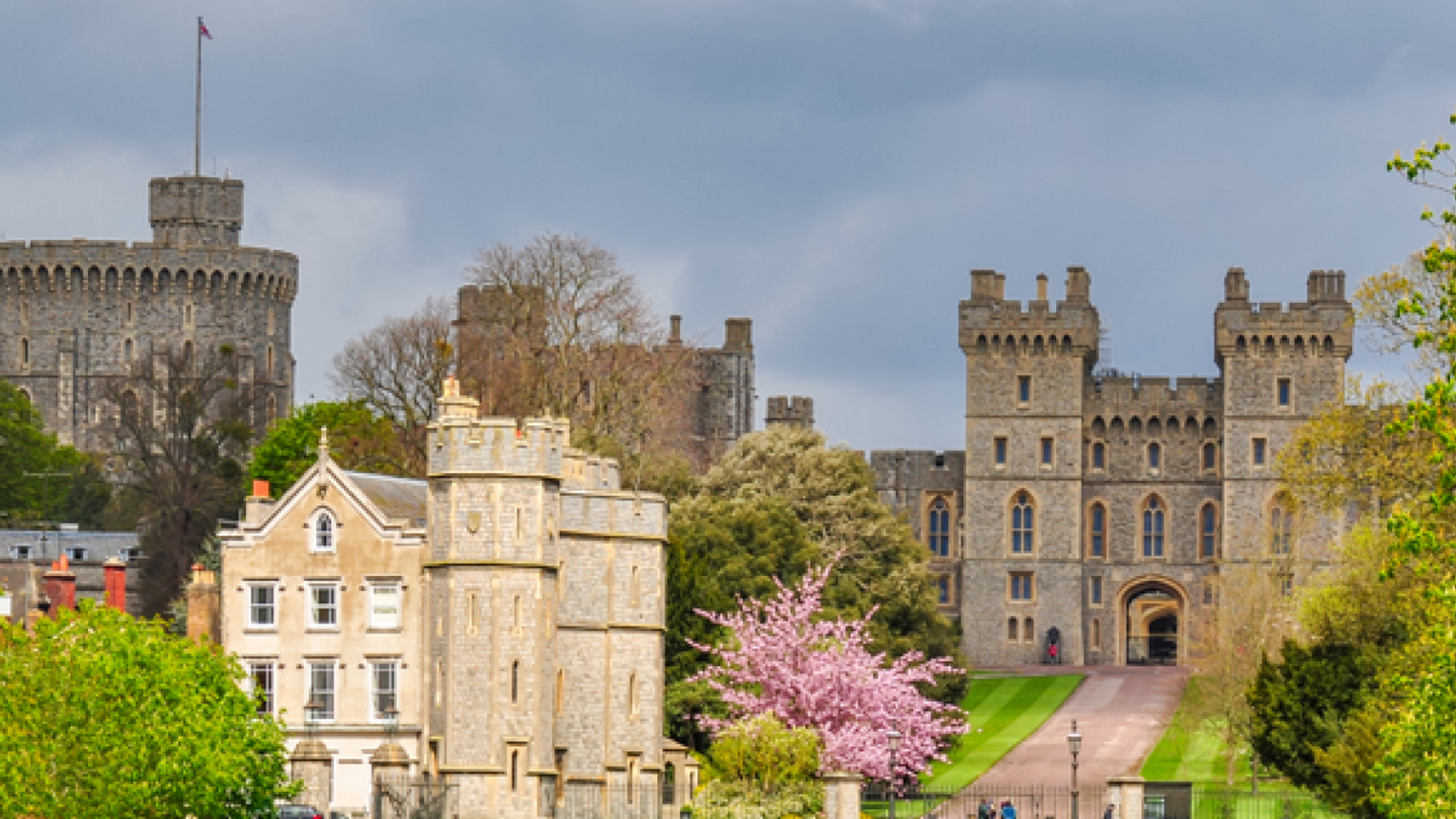 Windsor Castle with gate entrance leading into castle area. Its tower is to the left with a flag flying.