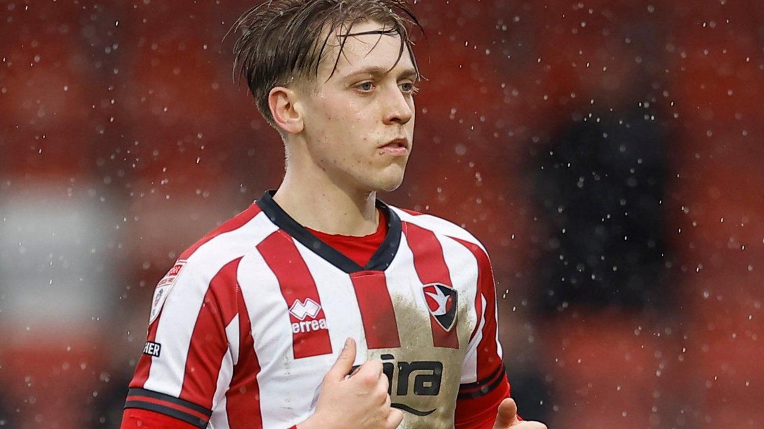 Jordan Thomas in action for Cheltenham Town in their red and white striped home shirt