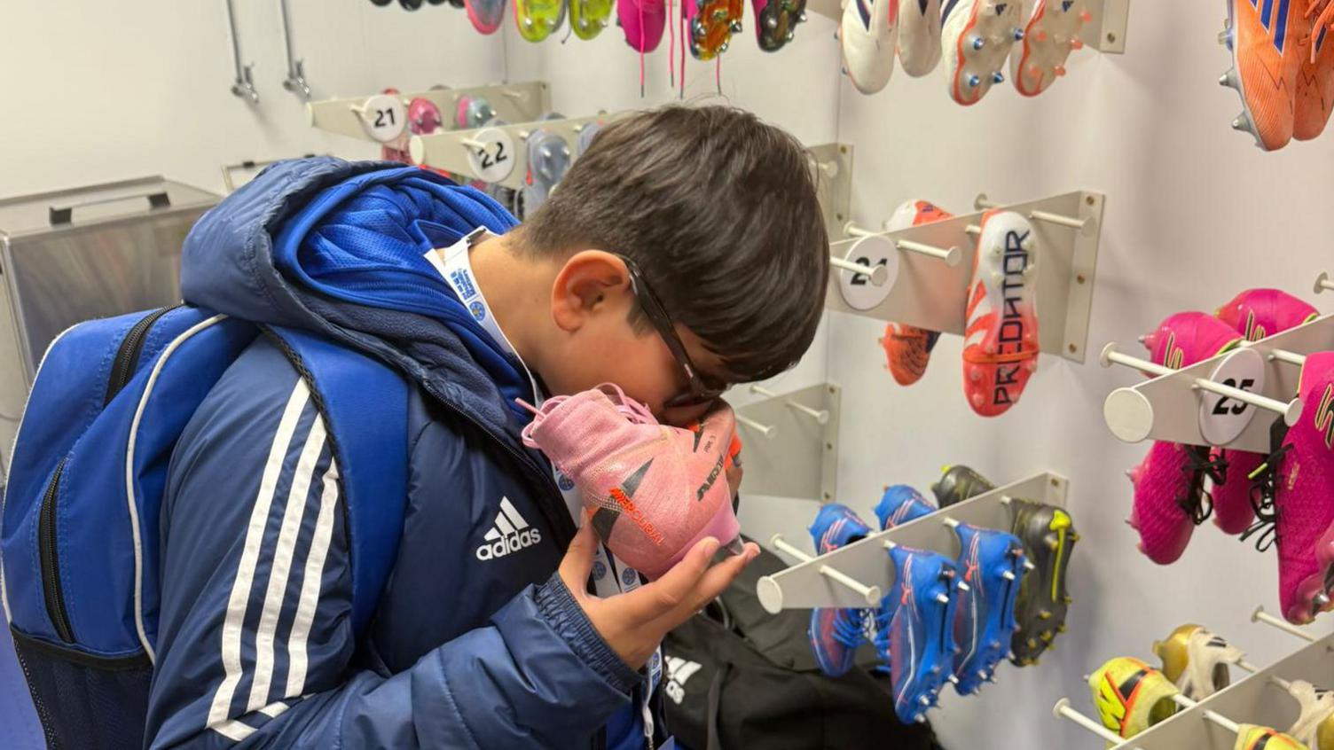 Teddy wearing Leicester City clothes kissing a pink boot