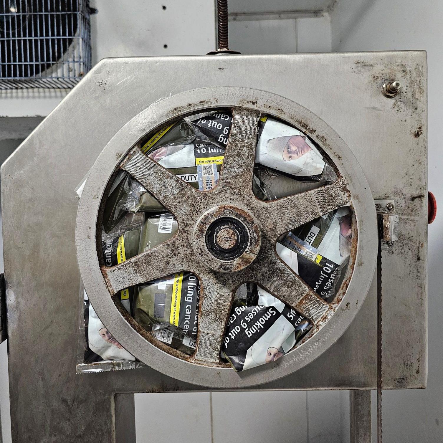 Packets of illegal tobacco wedged underneath a metal wheel on an item of machinery. 