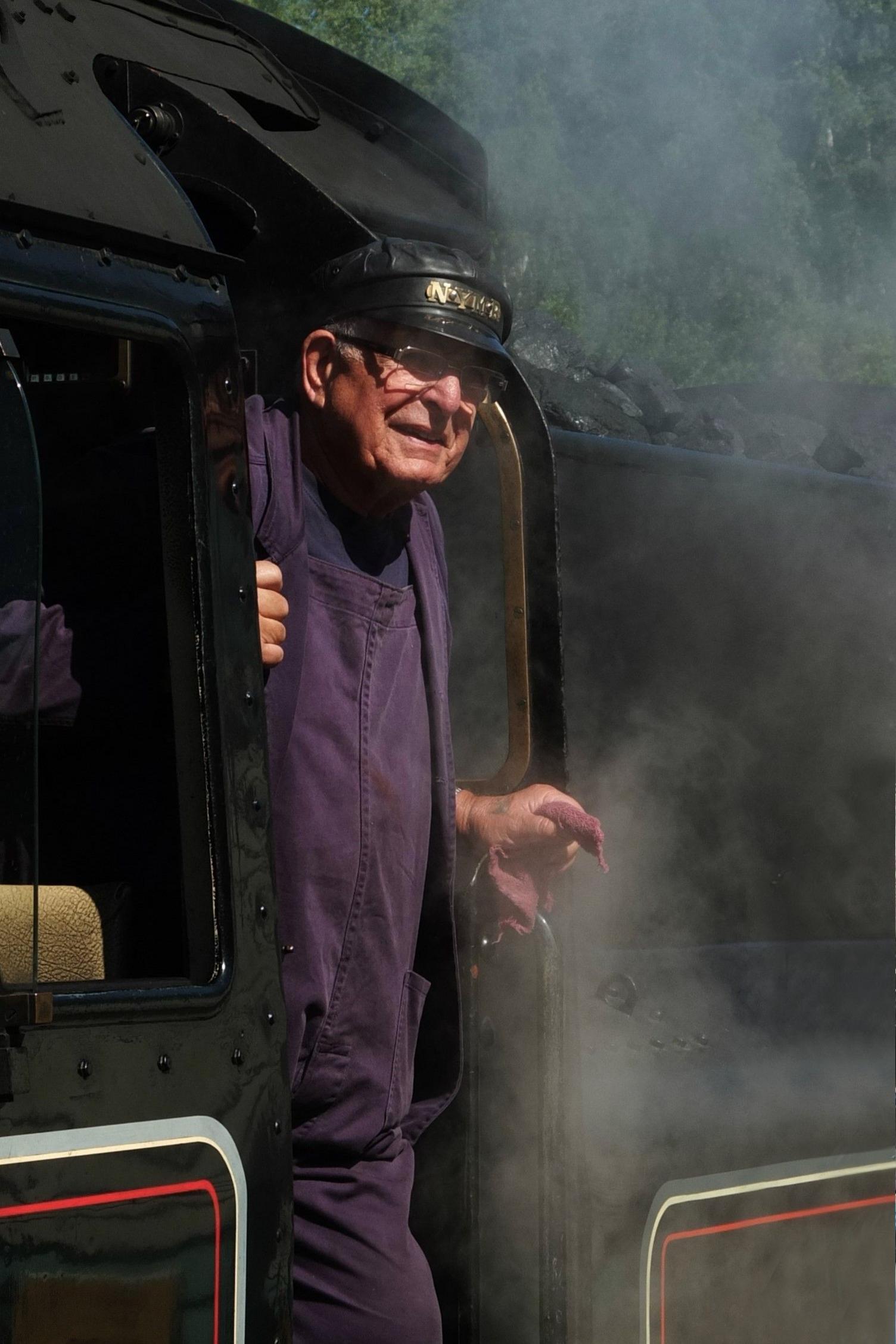 A man stands on the footplate of a steam locomotive