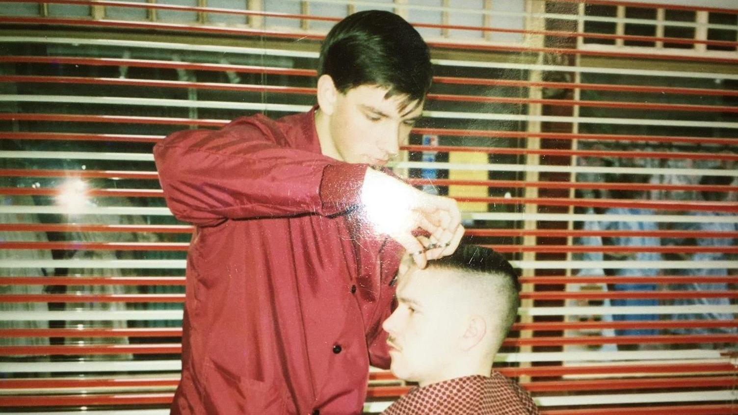 A picture from the 1980s showing a customer getting an American flat top haircut from  Phil Hutchinson. 