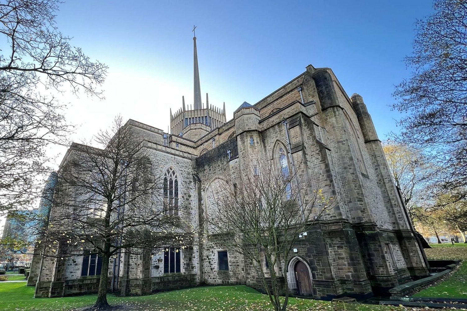 Blackburn Cathedral picture against a blue sky surrounded by trees  