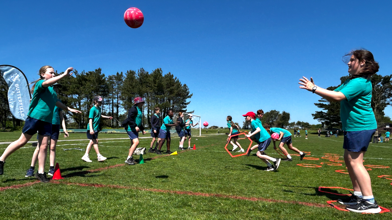 Students playing netball in Jersey. They are wearing green and blue uniforms.