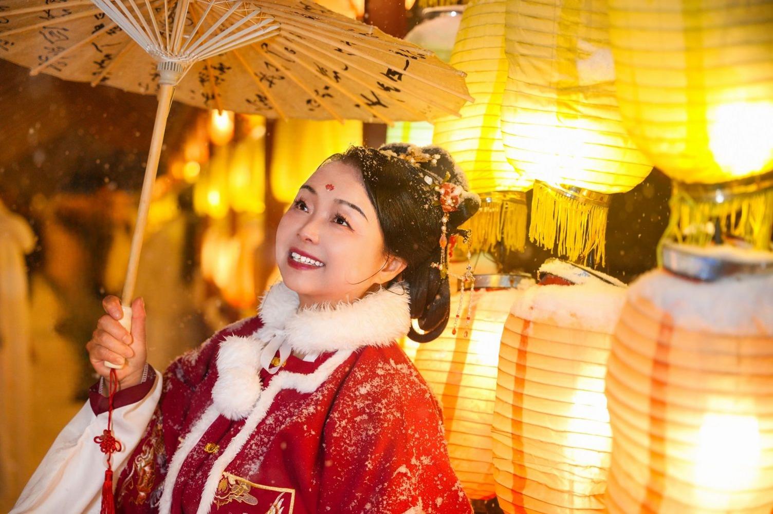  Su went back to her home province Henan, dressing in traditional Chinese costume. She is standing in a red dress with fur collar in front of several yellow paper lamps, lit from the inside