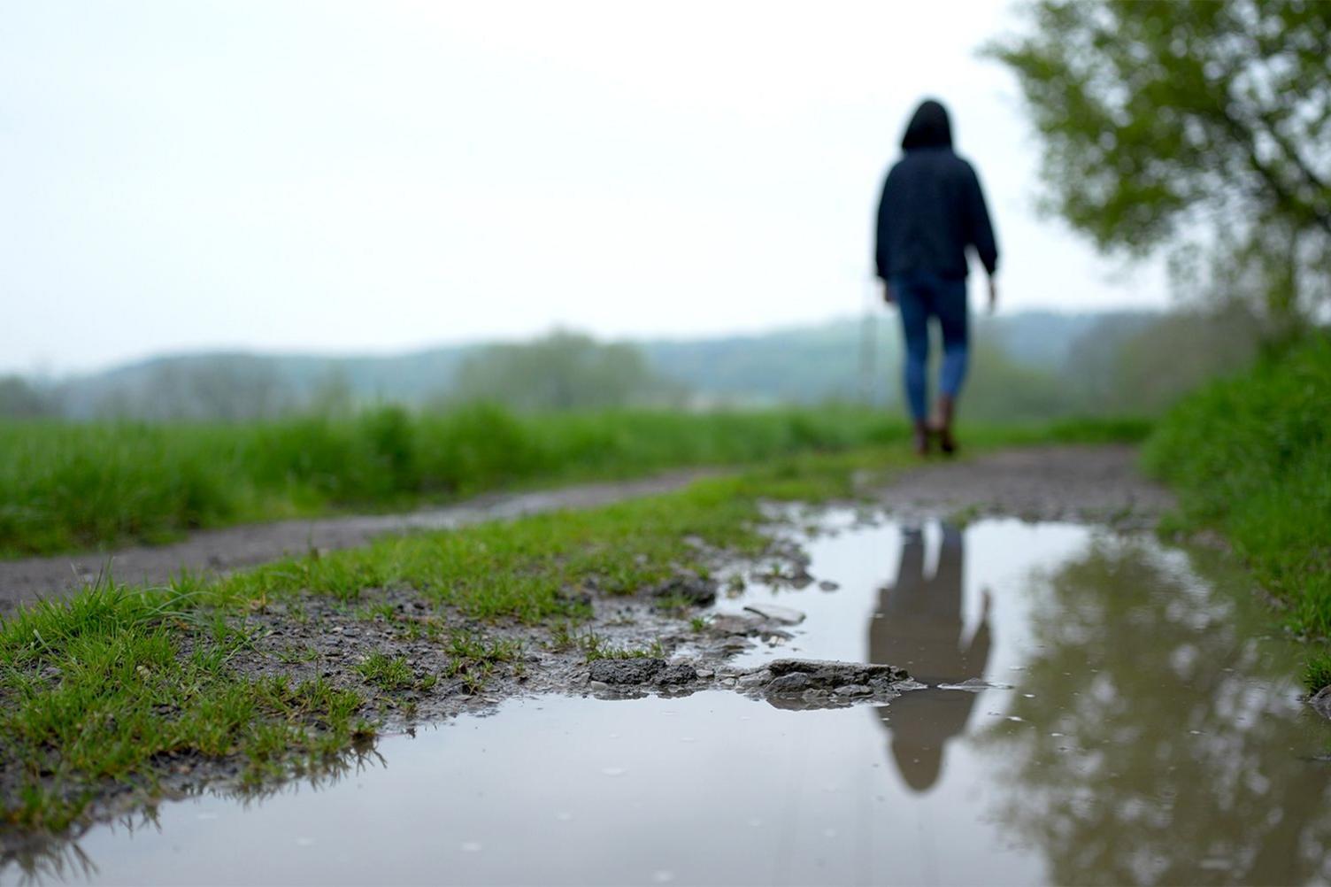 Samantha, her identity obscured, walking on a countryside path