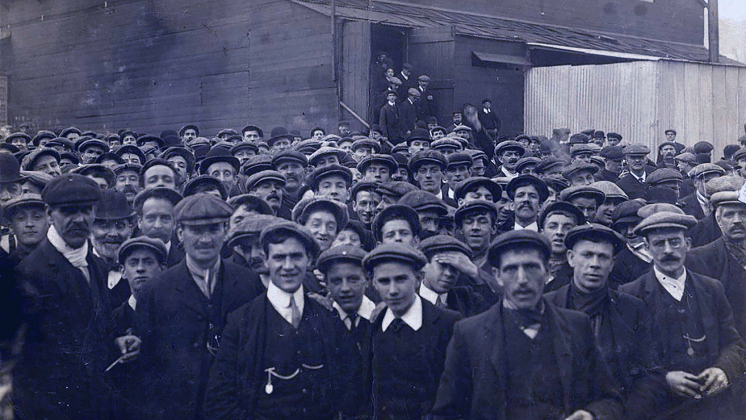 Massive crowd of striking miners, the majority in flat caps, shirt collars and jackets