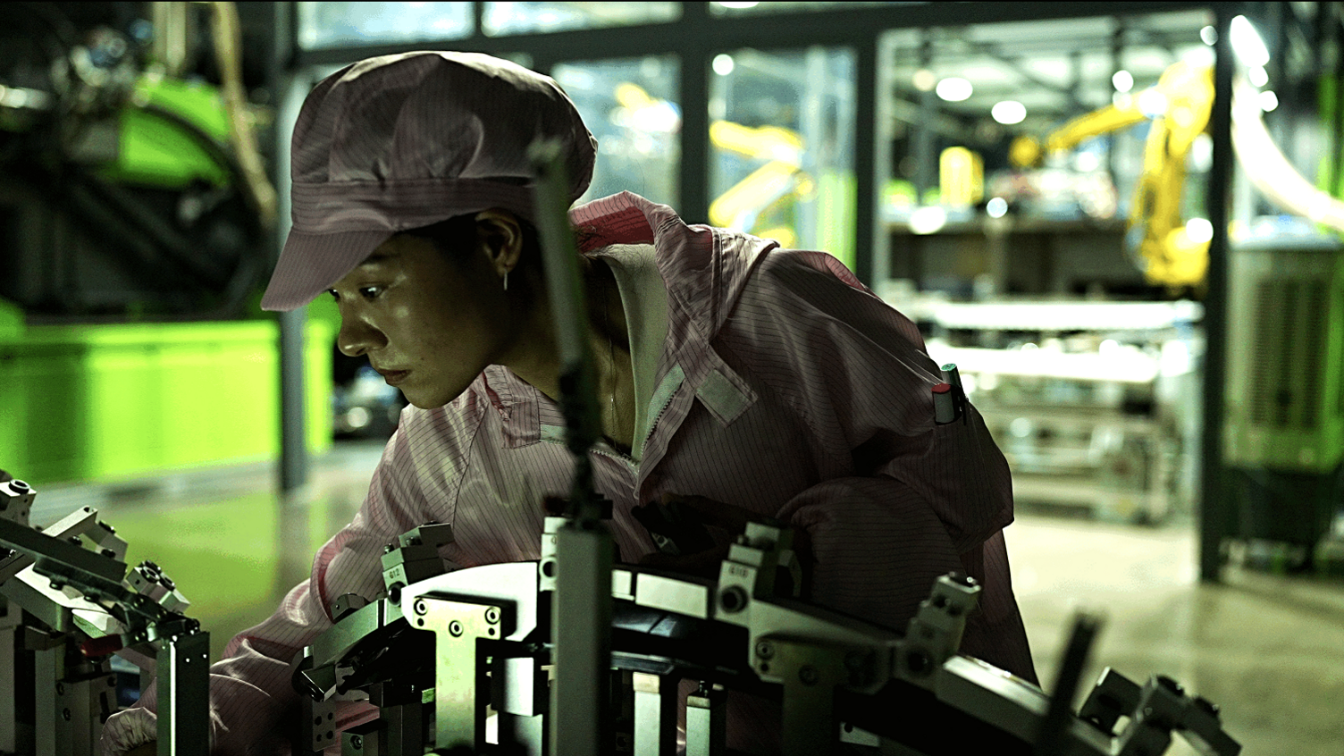 A young female worker examining a machine at the Leapfrog Motors factory. 