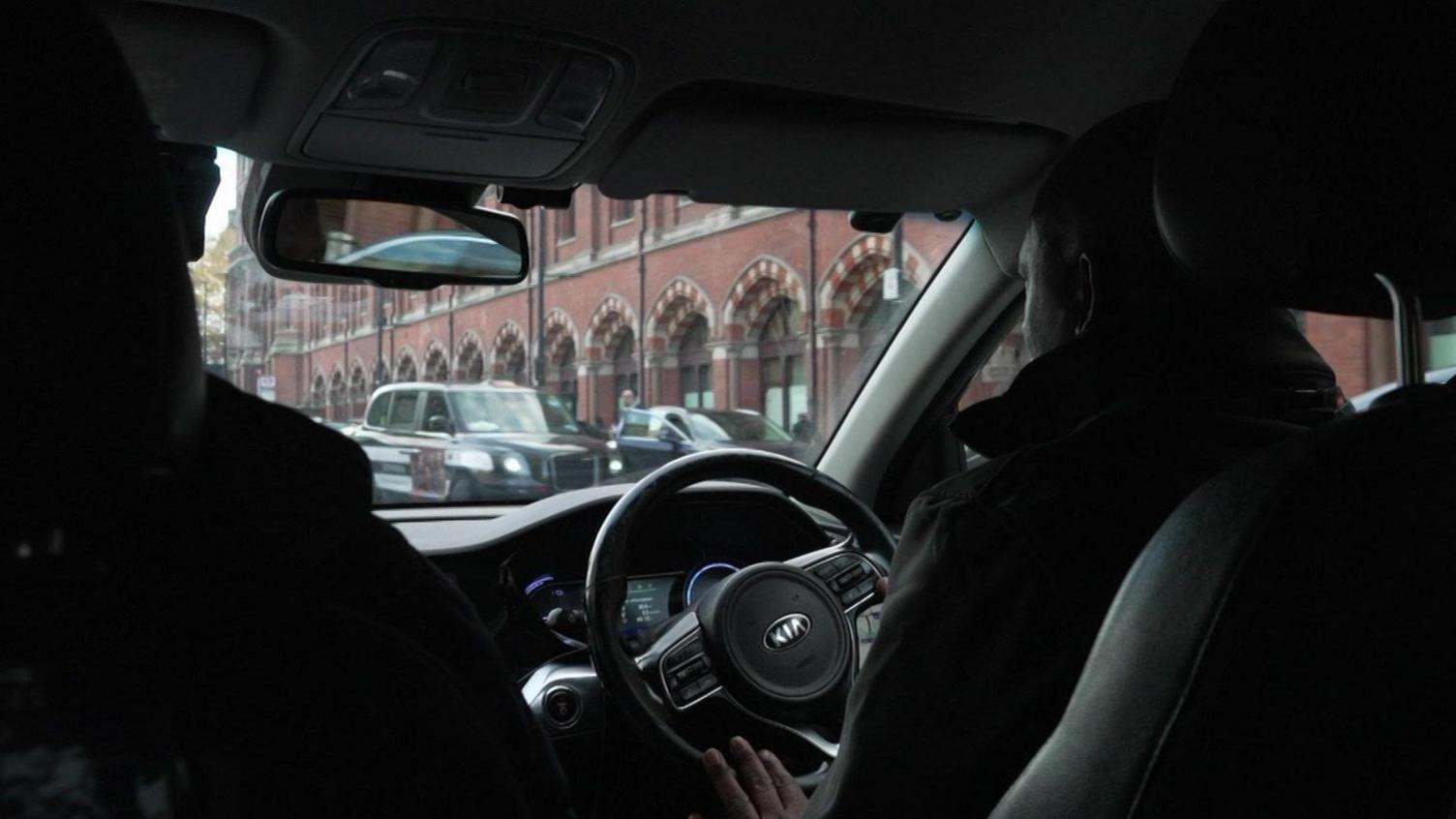 A man is sitting behind the wheel of a car