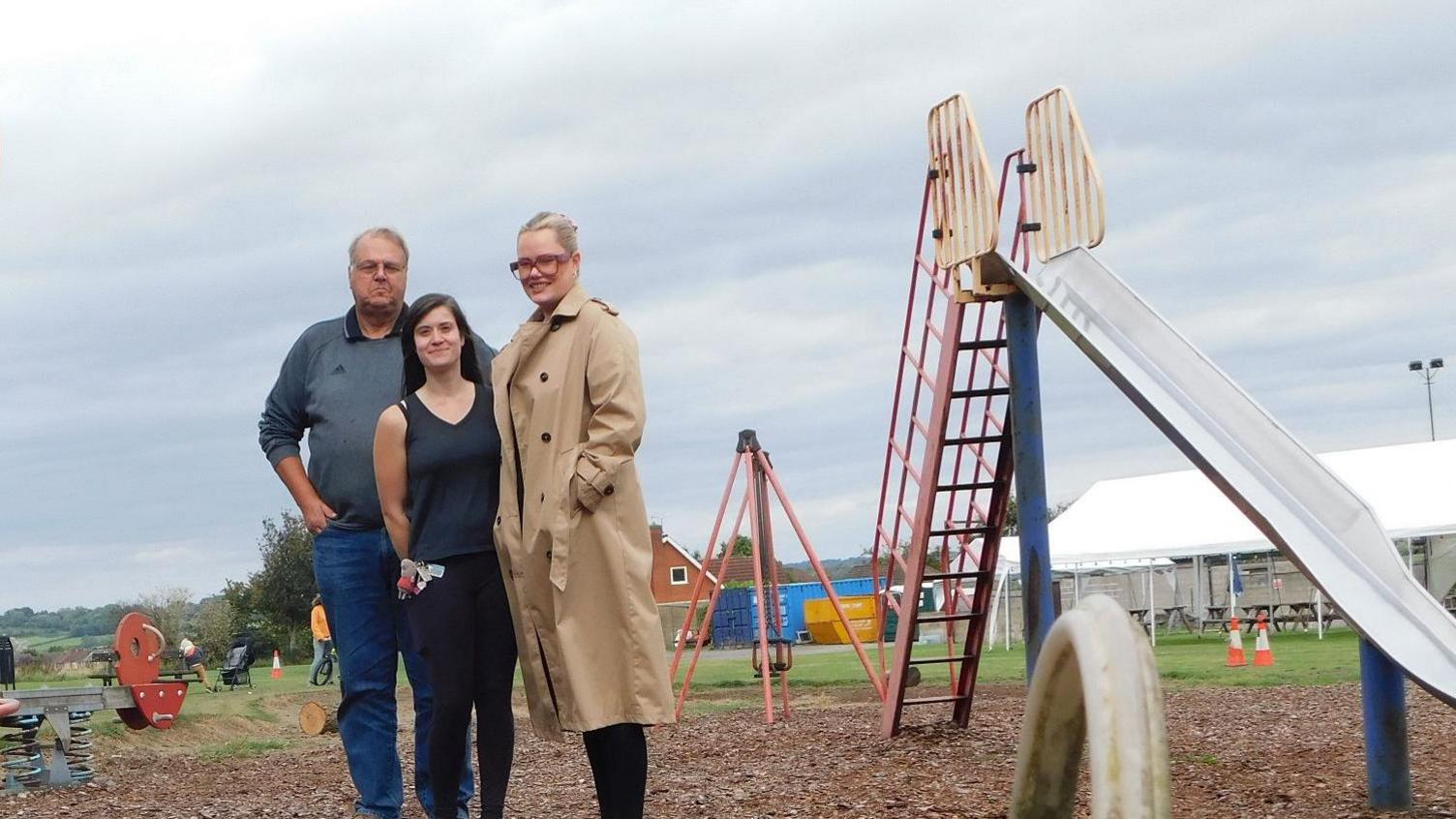 Three people stood in the middle of a children's play area