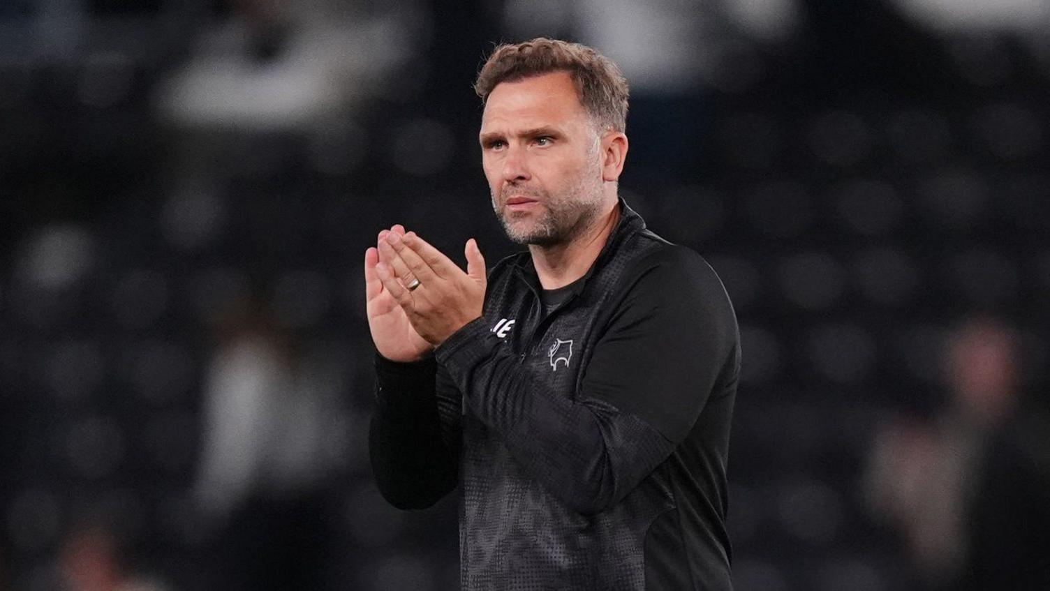 John Eustace walks on the pitch and claps his hands