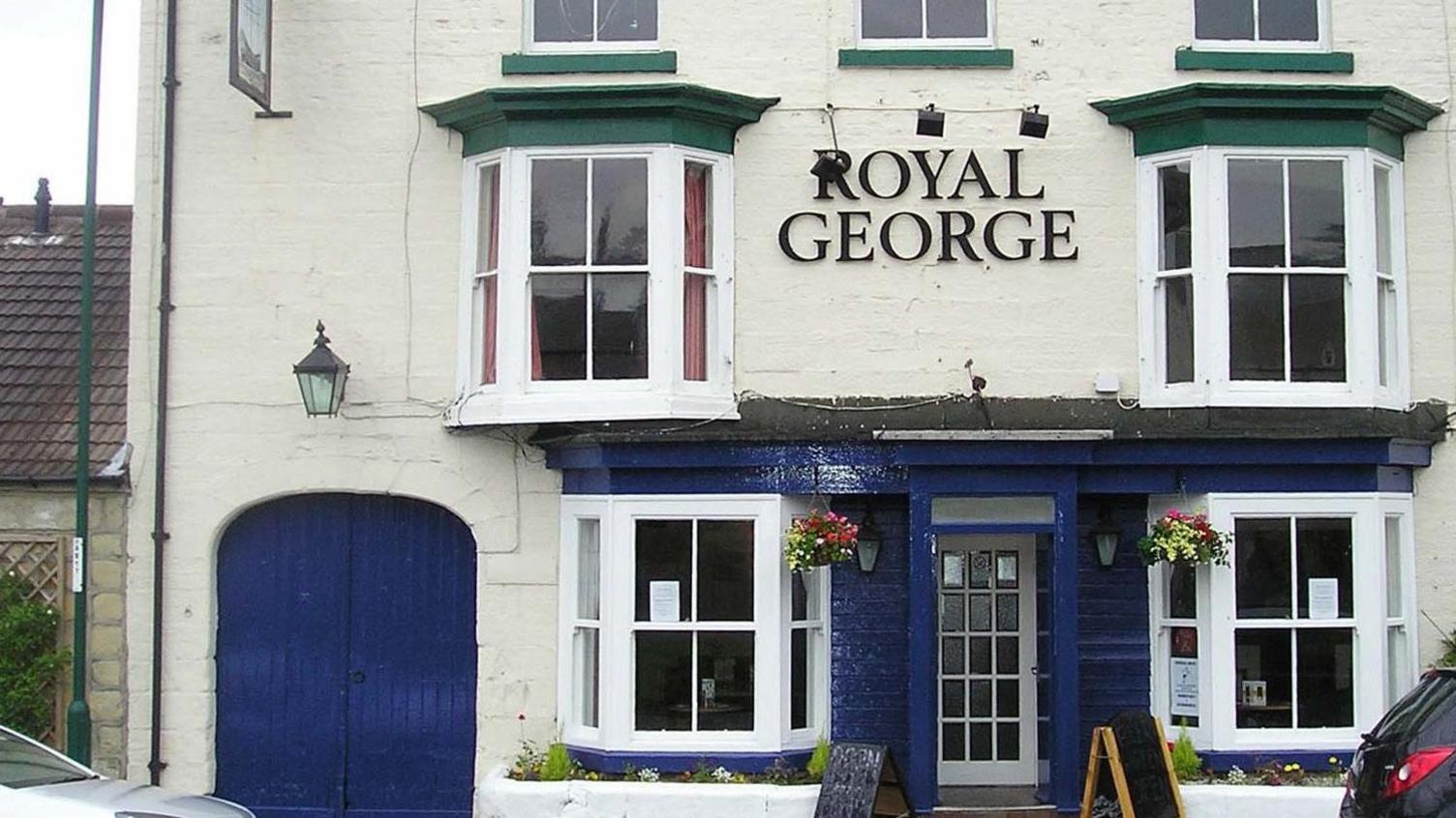 The Royal George pub: a three-storey brick building, painted white and blue.