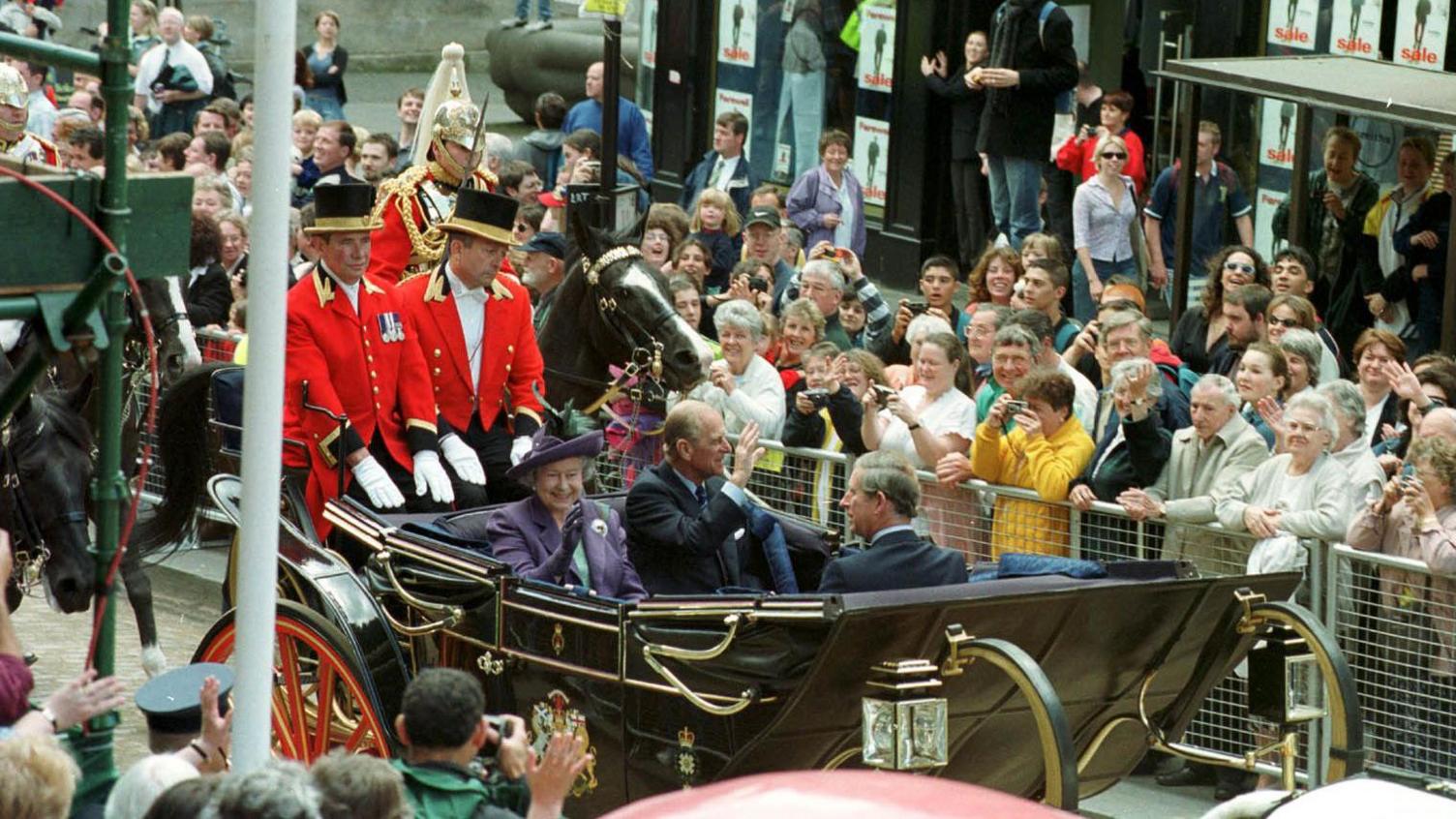 The Queen, the Duke of Edinburgh and Prince Charles attending the opening of the Scottish parliament in 1999. They are being taken to the Parliament in a horse-drawn carriage.