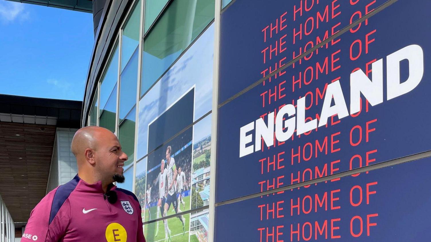 Fahd is looking at a banner that says "the Home of England"