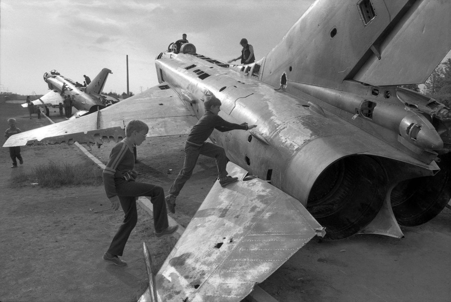 Boys playing on old Mig fighters