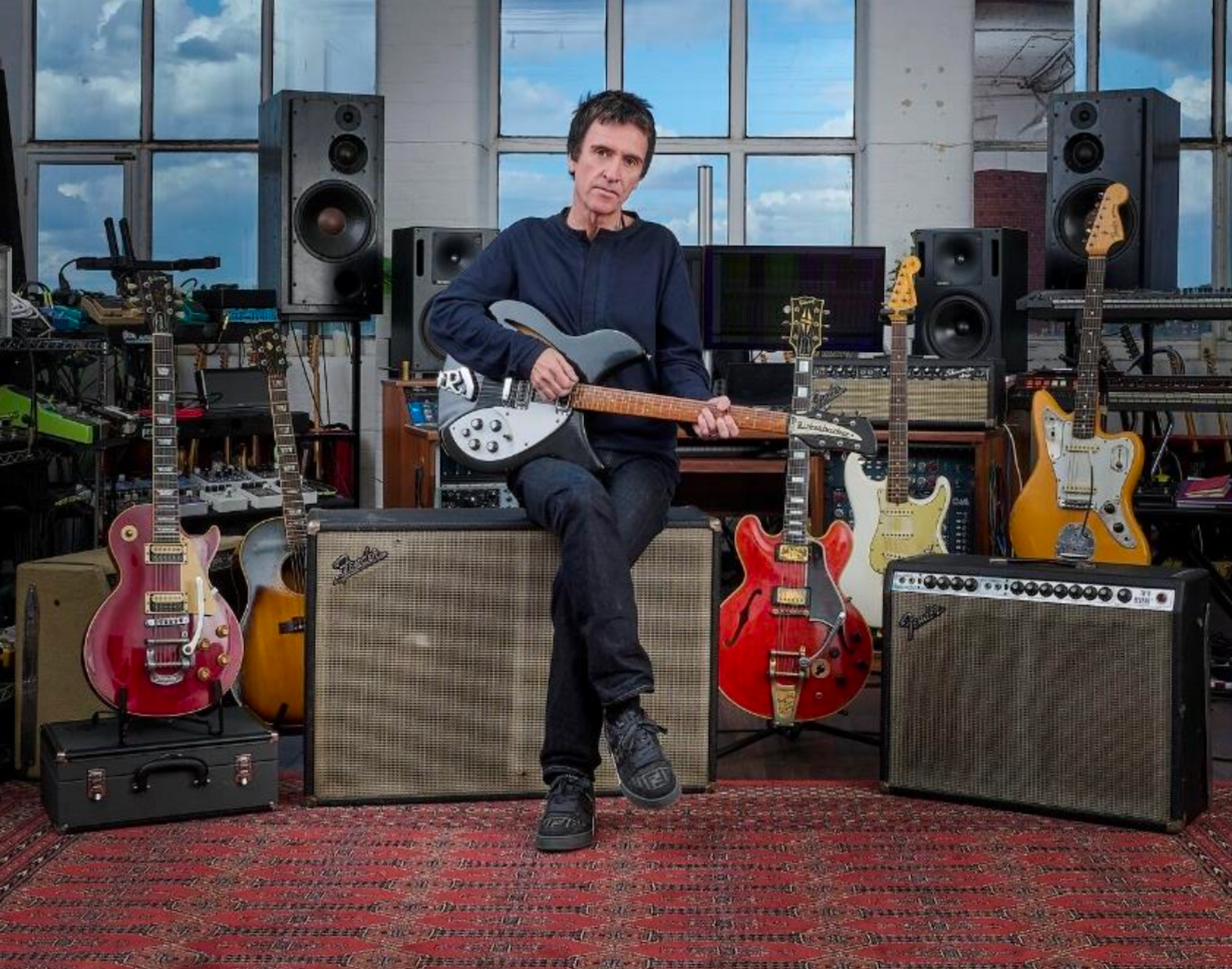 Johnny Marr poses with a series of guitars and amps