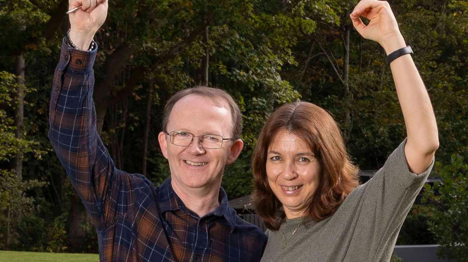 Richard and Yannick Baker smile at the camera with their arms in the air. 