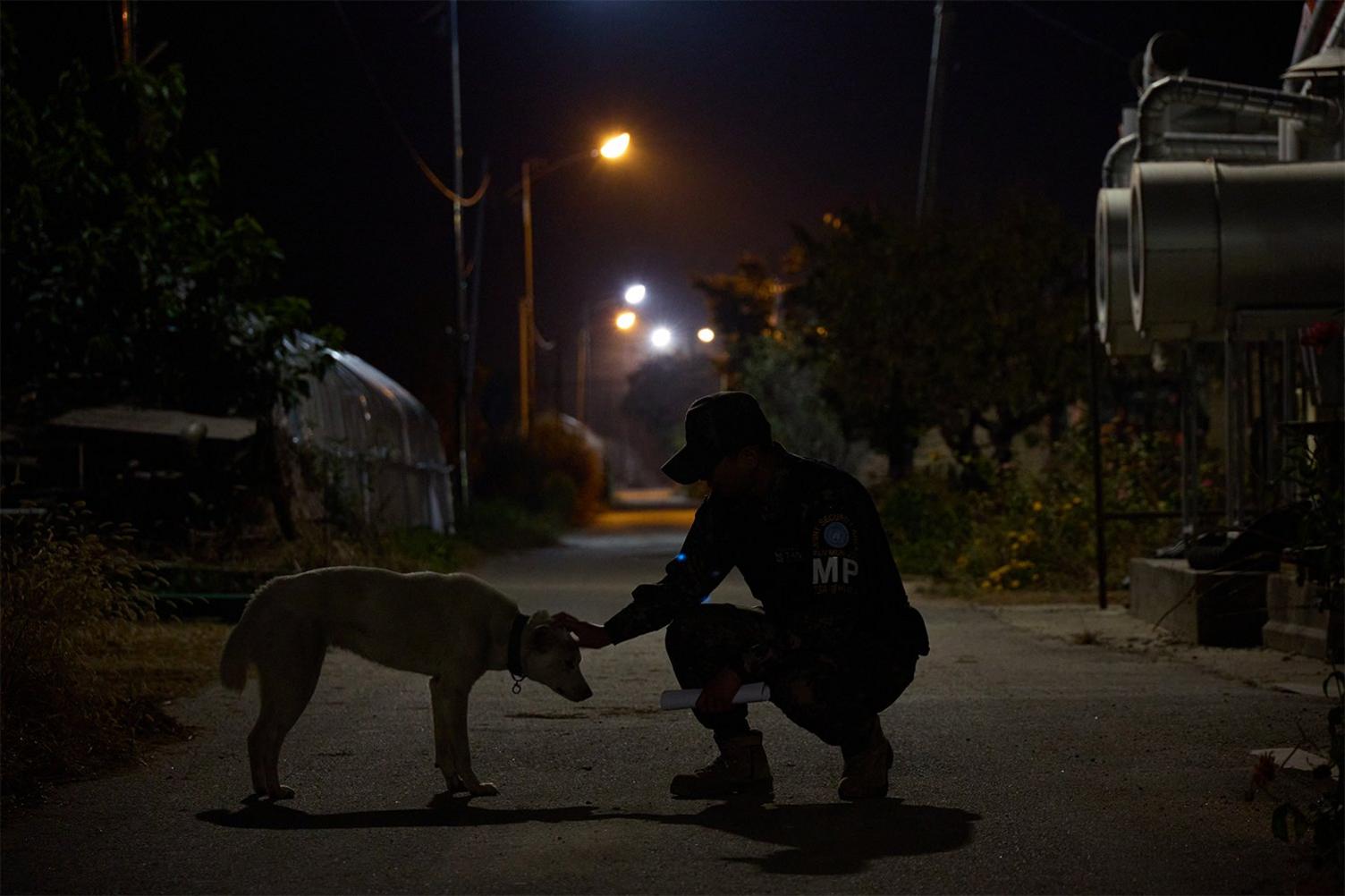 Soldier patrolling the village pets a dog