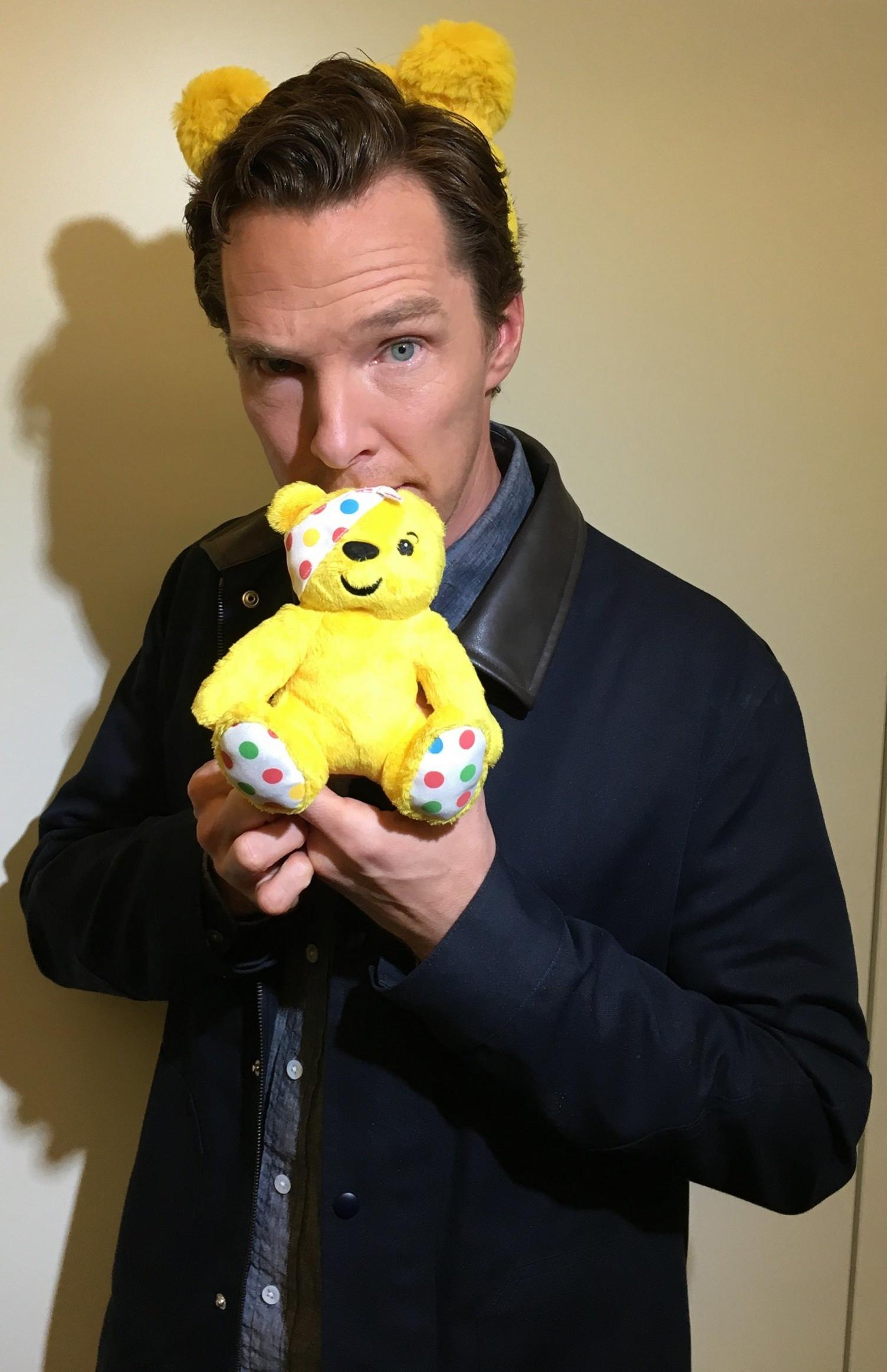 Benedict Cumberbatch holding a pudsey bear toy and wearing pudsey ears.