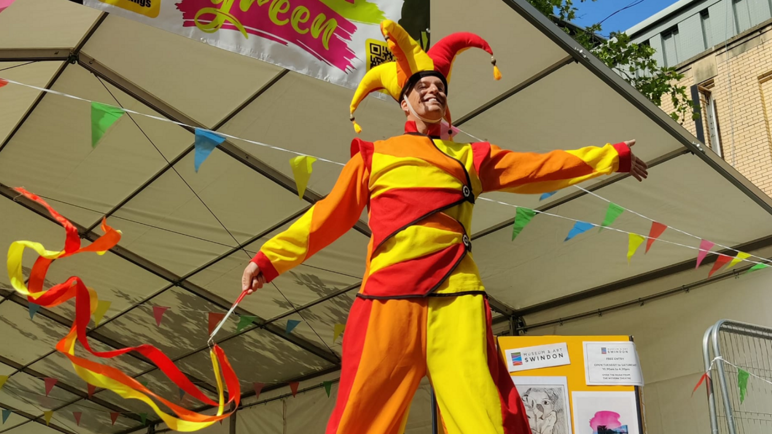 A man in jester costume performing on a stage