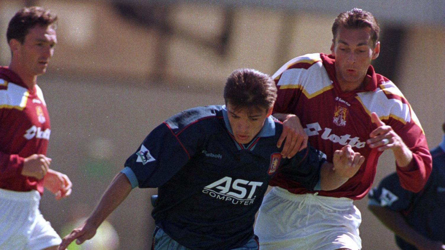 A Northampton Town defender attempts to tackle an Aston Villa player