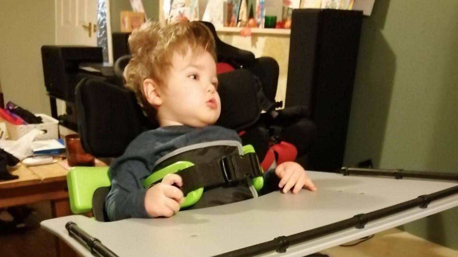 Kit at home in a chair with a table in front of him