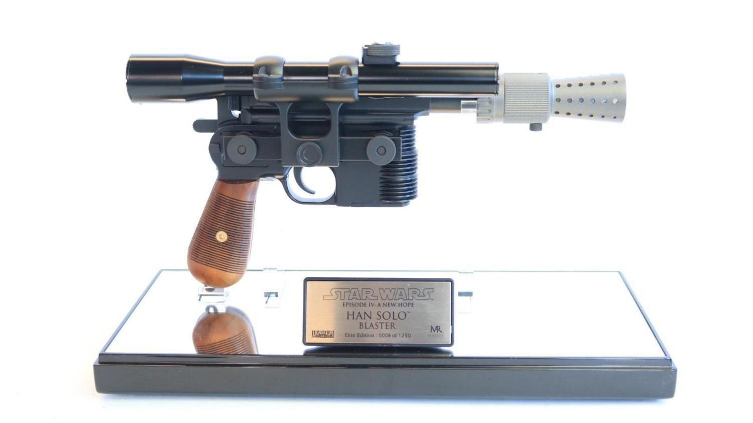 A model futuristic metal gun in a case with a plaque that reads "Han Solo blaster"