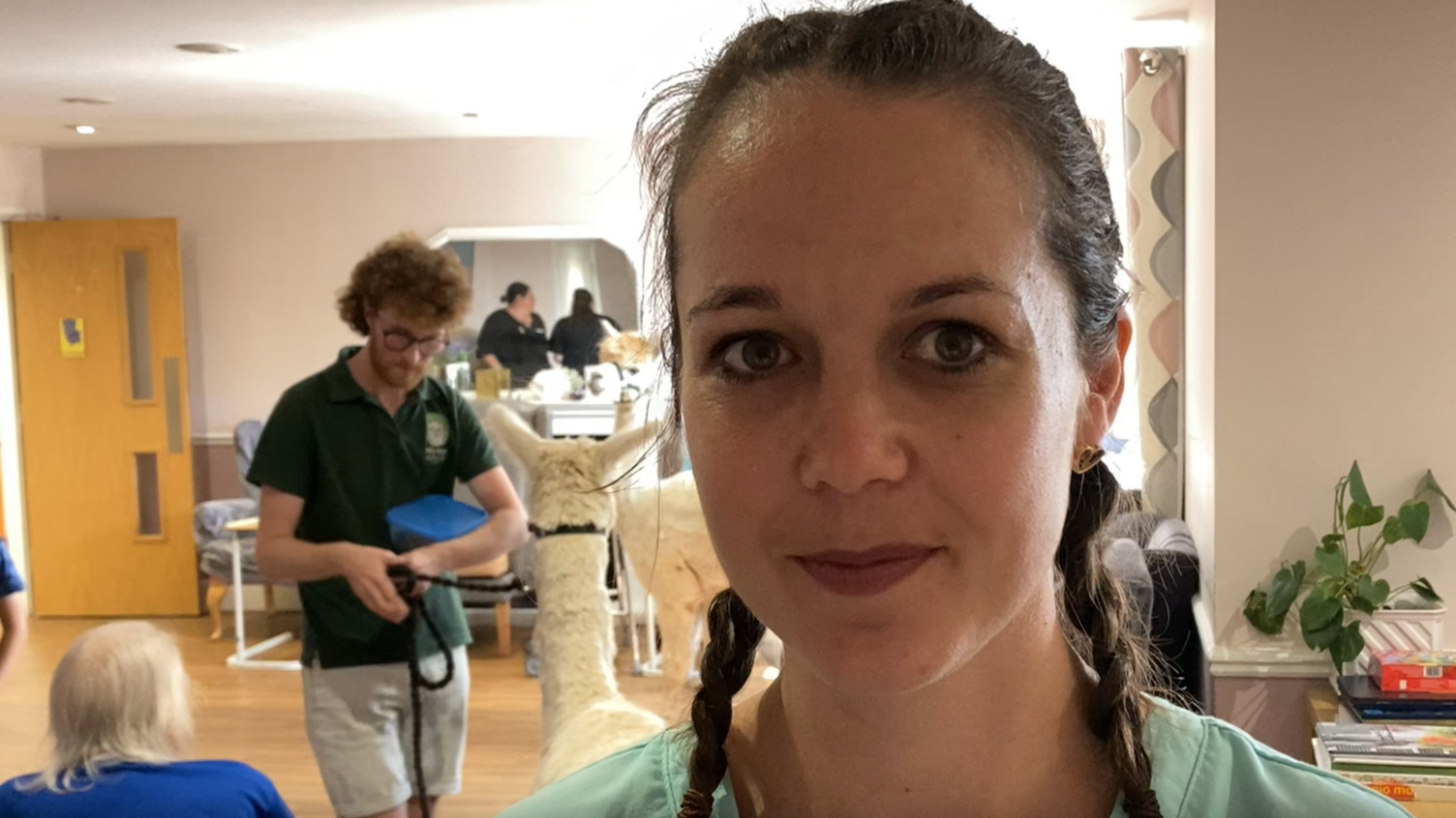 Magdalen House Care Home's activities manager Marianne Refurn with an alpaca and its handler inside the home in the background