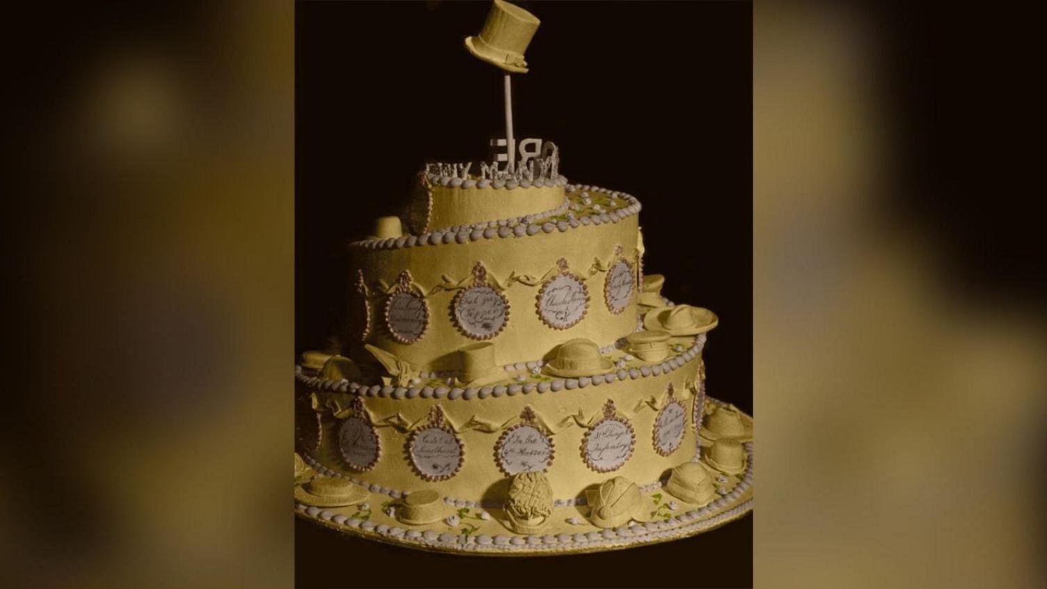 A golden circular cake with a top hat on top