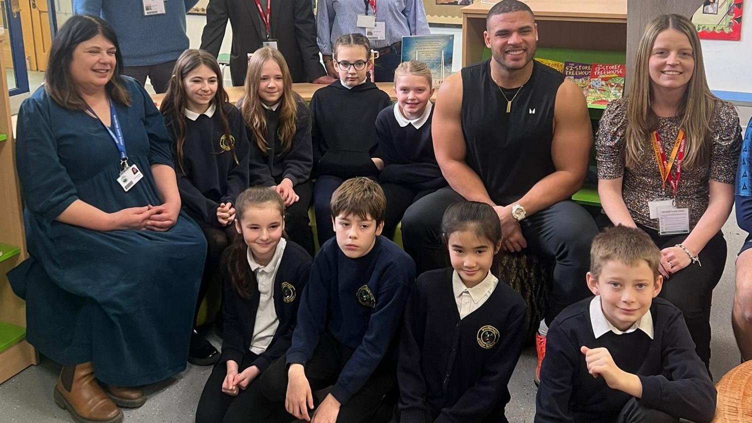 An image of several children and two female teachers sat with Zack George