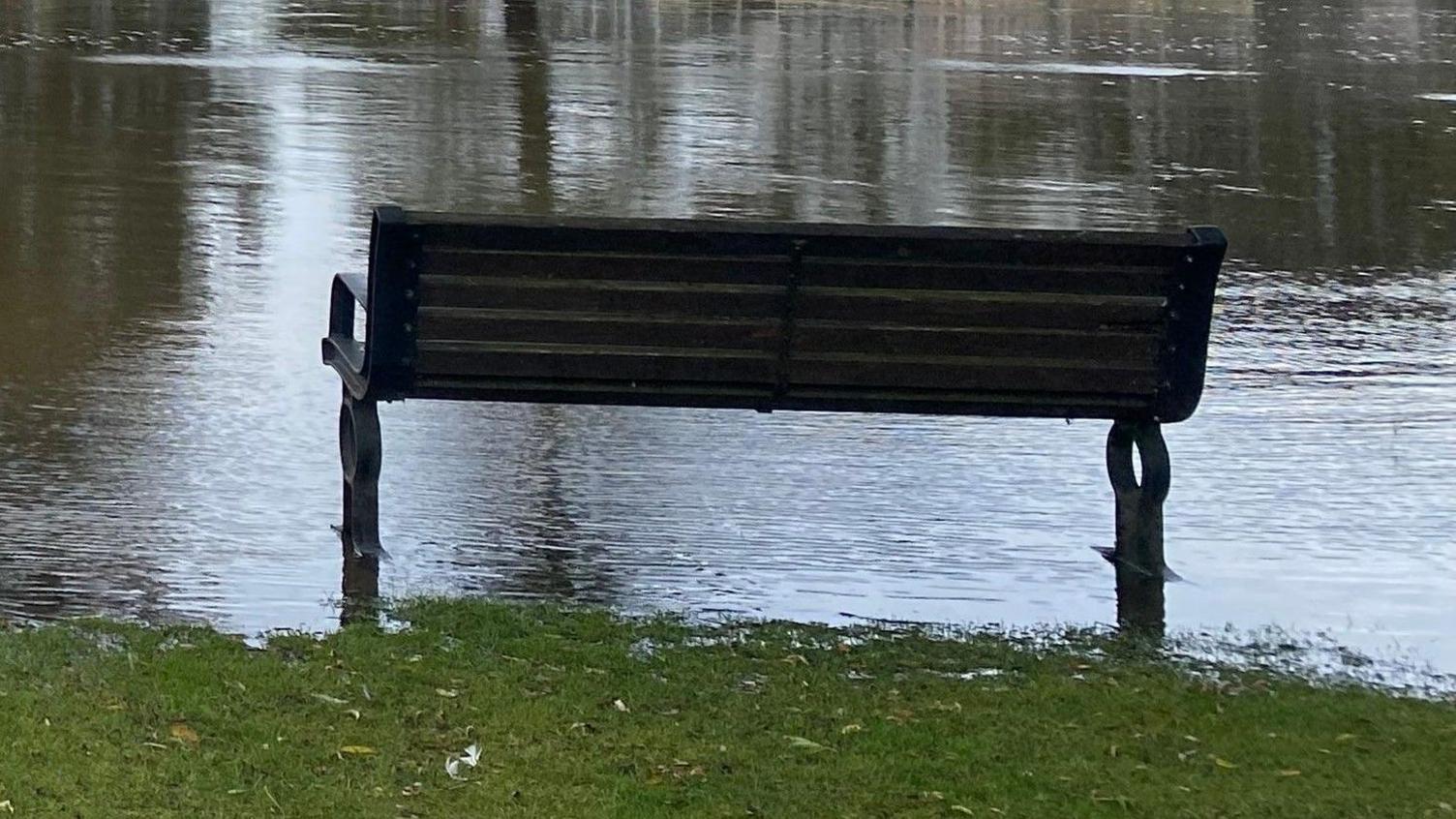 A park bench sitting in flood water