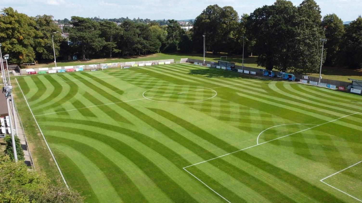 An aerial view of Westfields FC's pitch looking in very good condition. The markings on the pitch are clear and there are advertising boards on the perimeter
