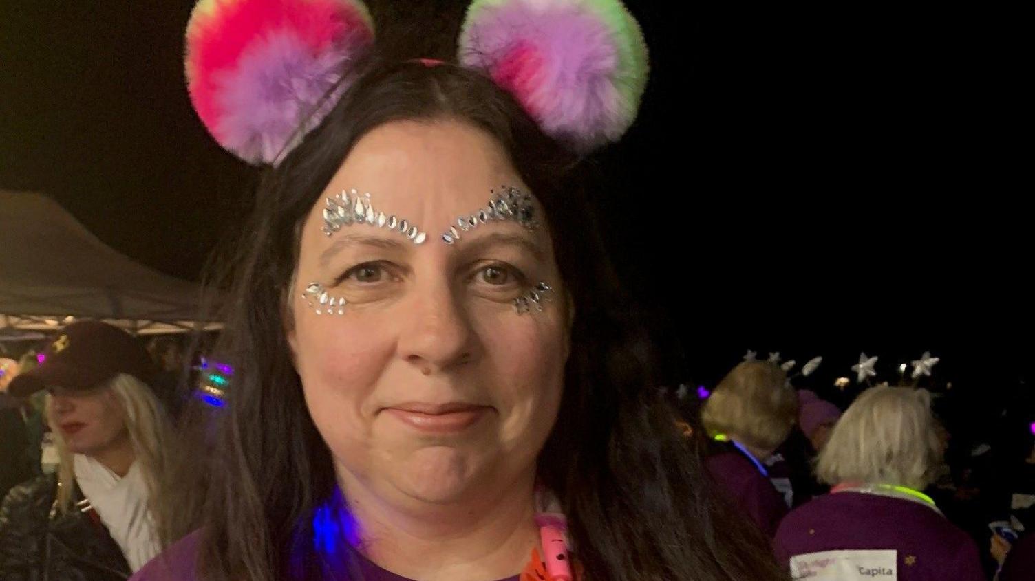 Sian Hart wearing fluffy ears at night time smiling at the camera.