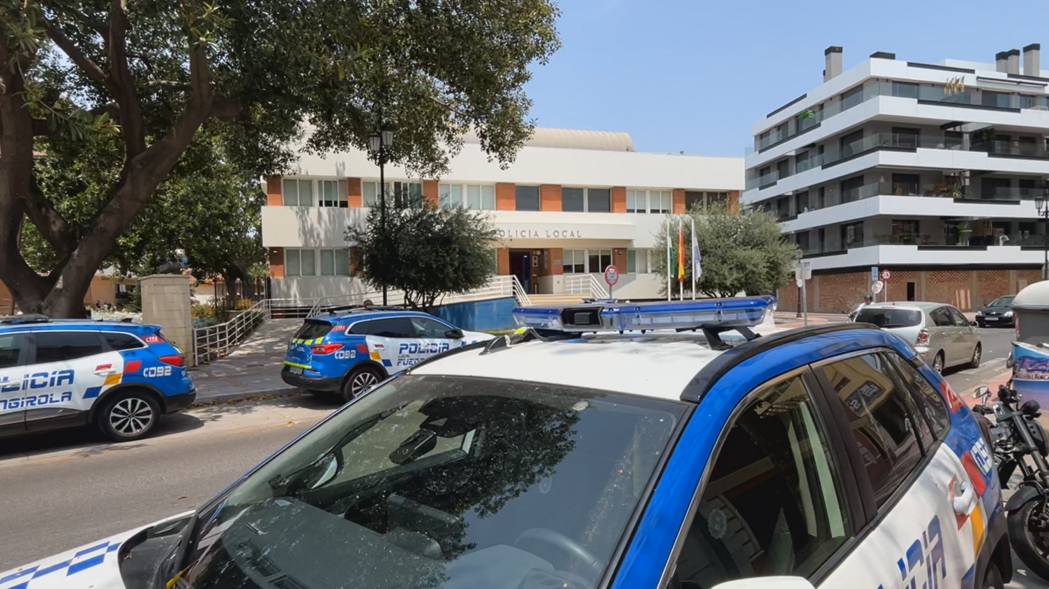 A Spanish police station with at least three blue and white police vehicles parked in the street outside.