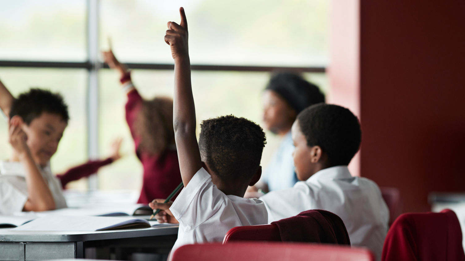 Children raising their hand in class