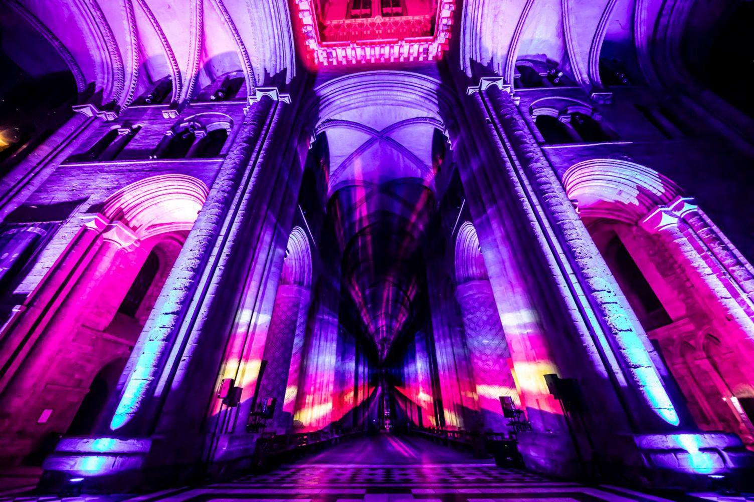 Inside the cathedral is lit up in yellow, purple, blue and pink. 