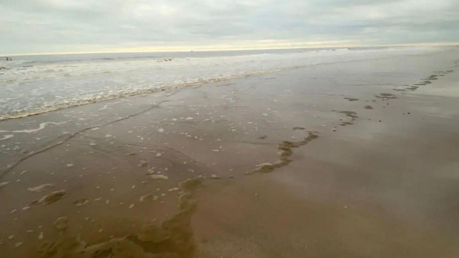 An empty, sandy beach with wide open skies.