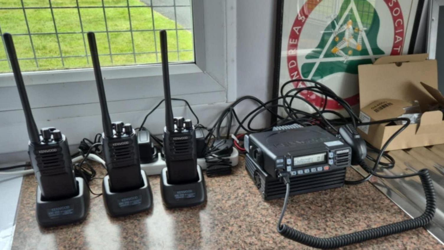 A close-up of three radios on a table and a receiver unit next to them.